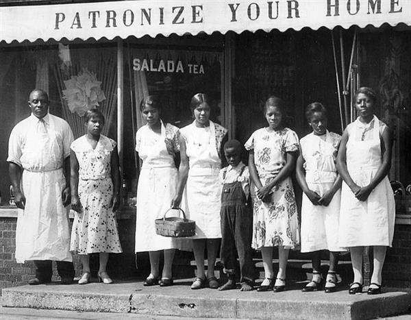 A group of people stand in front of the Harris Grocery Store